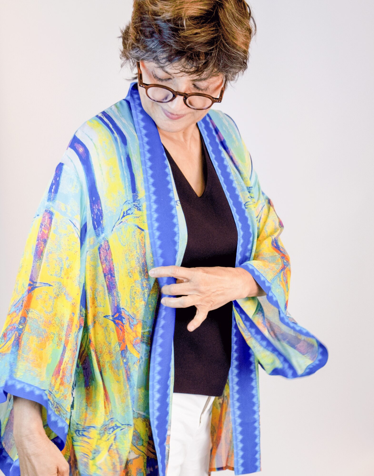 woman with glasses and short hair wearing multi color kimono with bird camouflaged in the print